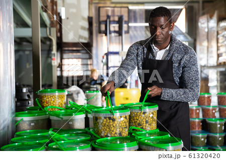 Man stacking plastic buckets with pickled olives 61320420