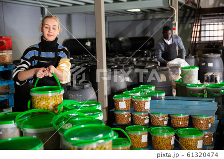 Girl arranging plastic buckets with pickled olives 61320474