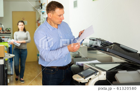 Worker is printing a file, document in the office room Worker is printing a file, document in the office room 61320580