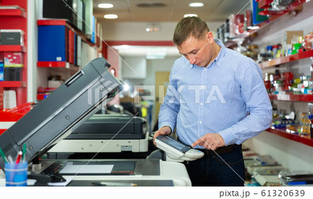 Worker is printing a file, document in the office room 61320639