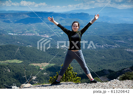 Happy woman with hands up on edge of mountain 61320642