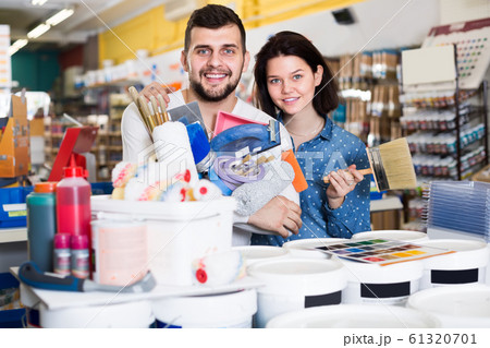 Young vigorous couple demonstrating tools for house renovating in paint store Young vigorous couple demonstrating tools for house renovating in paint store 61320701