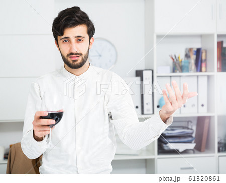 Office worker holding glass of red wine Office worker holding glass of red wine 61320861