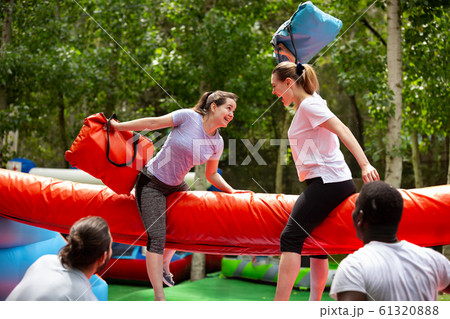 Women fighting by pillows on inflatable beam Women fighting by pillows on inflatable beam 61320888