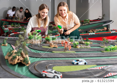 Emotional portrait of two women holding remote control and playing slot car racing 61321594