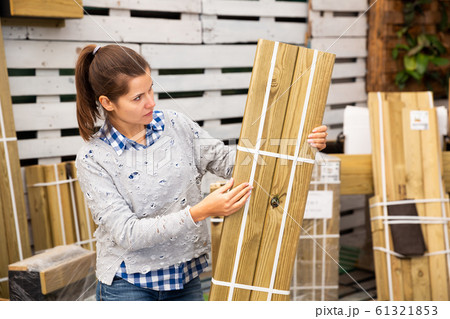 Woman choosing wooden panels at gardening store 61321853