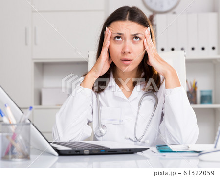 Upset practicioner girl is working with documents and laptop 61322059