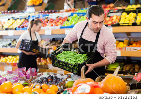 Young man with box of beans and woman wearing apron on background on the supermarket Young man with box of beans and woman wearing apron on background on the supermarket 61322163