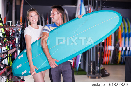 Adult guy with girl buying surfboard 61322329
