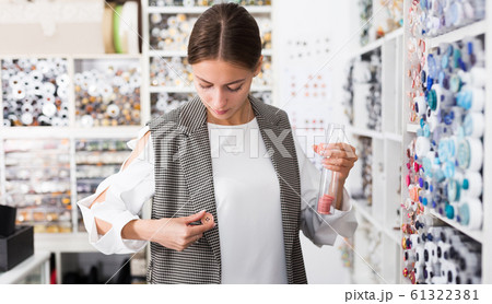 Woman choosing buttons in shop 61322381
