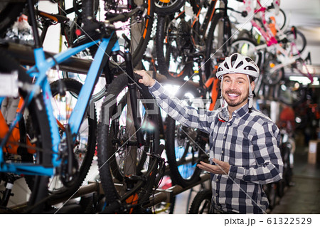 man in helmet chooses for himself sports bike in bicycle shop 61322529