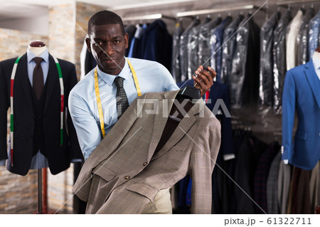 Male customer demonstrating his choice of suit in shop 61322711