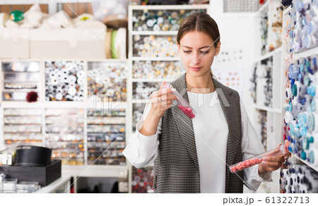 Seamstress looking for buttons in shop 61322713