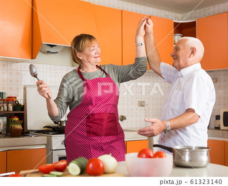 Senior man and woman dancing in kitchen 61323140