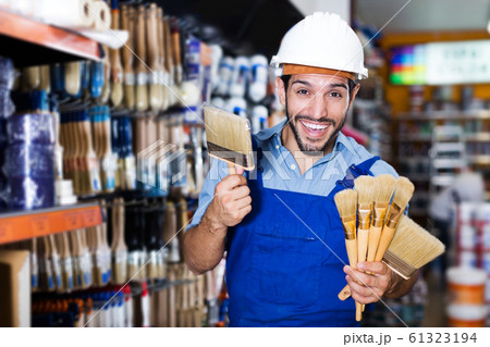 foreman in blue overalls choosing brushes 61323194