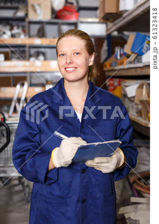 Young female worker holding notebook and looking construction materials at shelves 61323418
