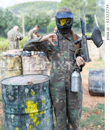 Female player in camouflage and black mask with traces of paint from hit markers Female player in camouflage and black mask with traces of paint from hit markers 61323734