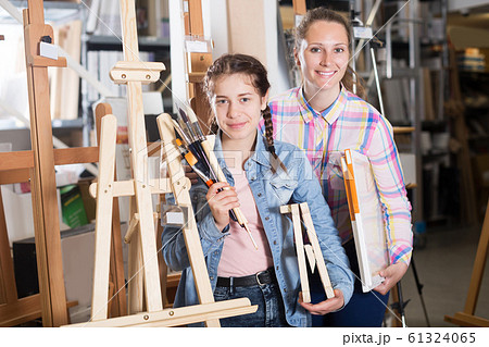 Mother and daughter standing among art supplies 61324065
