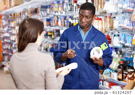 Competent seller consulting young woman about purchase of supplies for household works in store 61324207