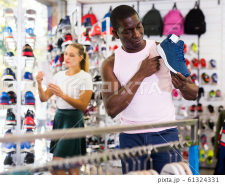 African man choosing sneakers in store African man choosing sneakers in store 61324331