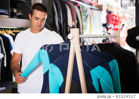 Man choosing new wetsuit in shop 61324517
