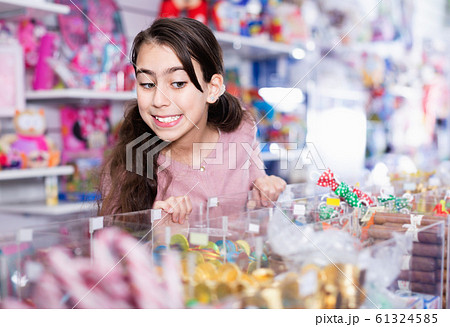Emotional small girl choosing sweet candies in the candy shop Emotional small girl choosing sweet candies in the candy shop 61324585
