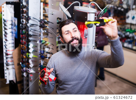 happy male customer examining sunglasses in sports equipment store 61324672
