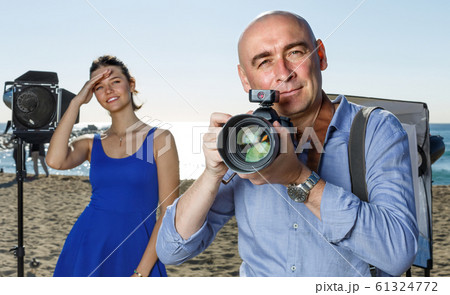 Portrait of photographer with his camera during photo shooting on sea coast Portrait of photographer with his camera during photo shooting on sea coast 61324772