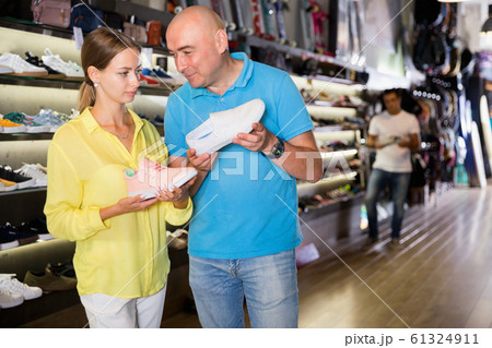 Male and female customers shopping together, searching sneakers in store 61324911