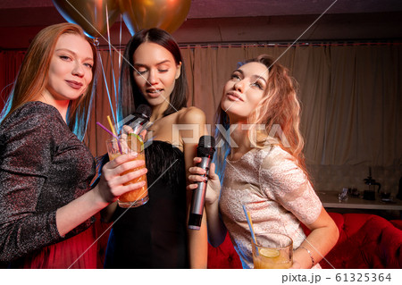 Portrait of happy caucasian women singing in microphone in karaoke bar 61325364