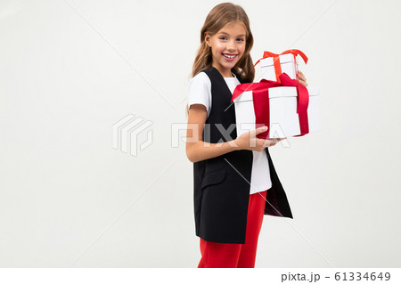 Teenager caucasian girl in black jacket, white shirt and red pants holds a white boxes with gifts Teenager caucasian girl in black jacket, white shirt and red pants holds a white boxes with gifts 61334649