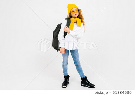 stylish caucasian charming girl in a white shirt, blue jeans, a yellow hat, with a backpack on his 61334680