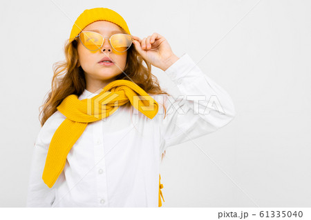 close-up portrait of an attractive smiling girl in a yellow hat and sunglasses, in a white shirt 61335040