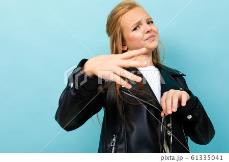 Pretty caucasian teenager girl with long brown hair in black jacket and denim jeans holds yellow 61335041