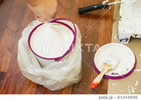 Person mixing white paint in bucket. Person mixing white paint in bucket. 61343040