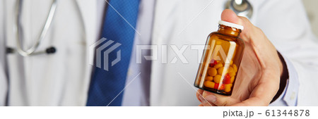 Male medicine doctor hand holding and offering to patient jar of pills 61344878
