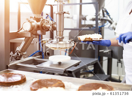 Modern equipment for the manufacture of cakes. Smear cream on cake. Confectionery, automatic Modern equipment for the manufacture of cakes. Smear cream on cake. Confectionery, automatic 61351736