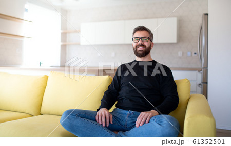 Cheerful mature man sitting on sofa in unfurnished house. 61352501