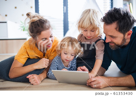 Young family with two small children indoors in bedroom, using tablet. Young family with two small children indoors in bedroom, using tablet. 61353430