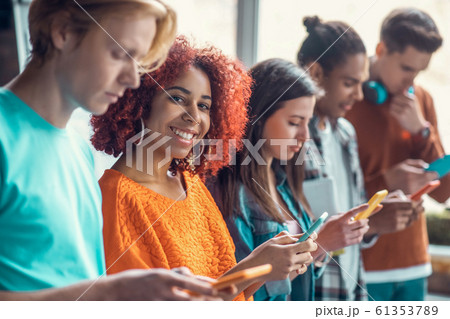 Student smiling standing near friends and using social media Student smiling standing near friends and using social media 61353789