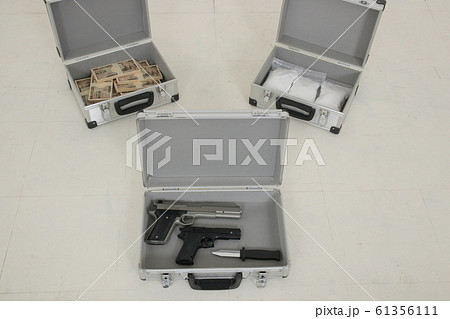 アタッシュケースに入った札束と覚醒剤とピストルの写真素材