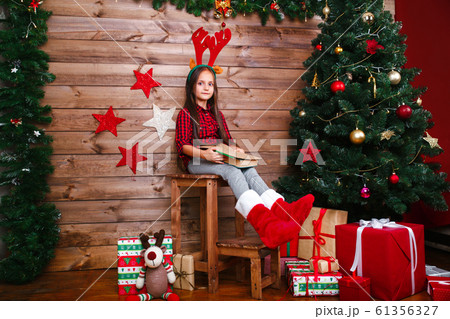 Funny child girl writes letter to Santa near christmas tree 61356327