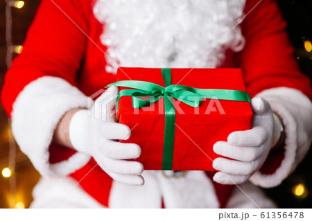Red gift in Santa Claus hands near Christmas background 61356478