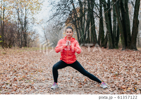 Stretching and exercising. Young sporty fit girl doing sports in autumn park . 61357122