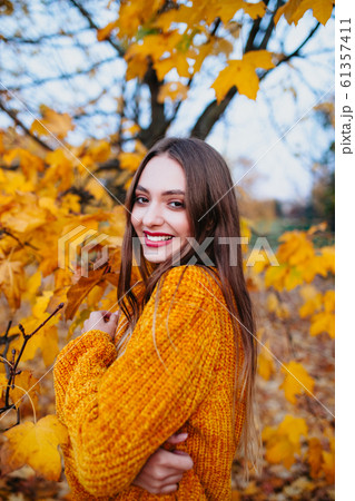 Beautiful woman with red lips in bright yellow sweater enjoying in a sunny autumn day Beautiful woman with red lips in bright yellow sweater enjoying in a sunny autumn day 61357411