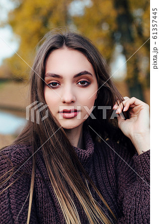 Close-up portrait of romantic beautiful young woman in autumn park. 61357445