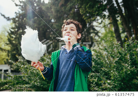 Happy child eating cotton candy at carnival in park Happy child eating cotton candy at carnival in park 61357475