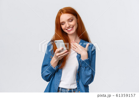 Oh so cute. Touched and pleased alluring redhead girlfriend receive love emoji, lovely message, texting, chatting boyfriend, holding smartphone, touch chest and smiling mobile display Oh so cute. Touched and pleased alluring redhead girlfriend receive love emoji, lovely message, texting, chatting boyfriend, holding smartphone, touch chest and smiling mobile display 61359157