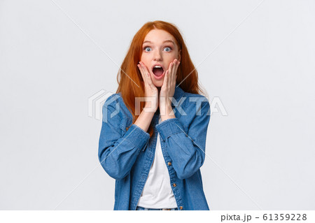 Oh my gosh, amazing. Surprised speechless redhead woman standing starled and shocked, touch face, drop jaw and stare camera fascinated, got job, won prize, standing white background 61359228