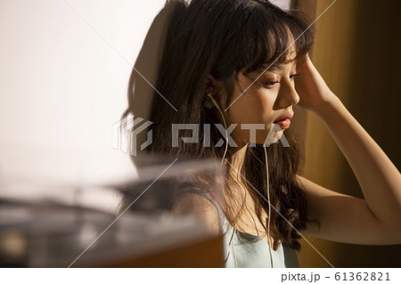 音楽を聴いて黄昏れる女性 61362821